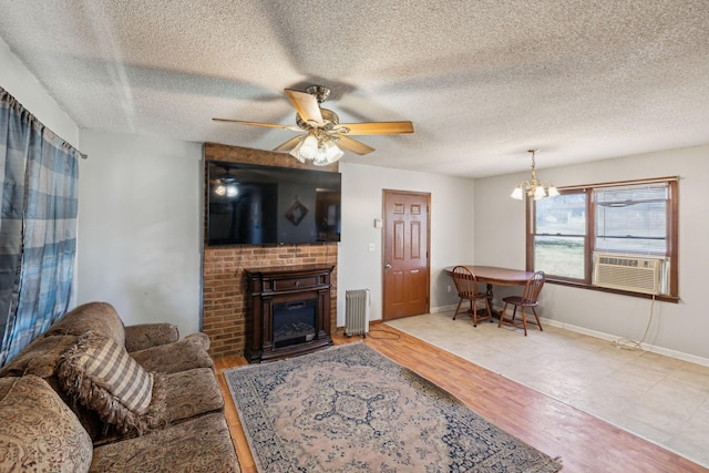 living room with cooling unit, a fireplace, ceiling fan with notable chandelier, and light wood-type flooring