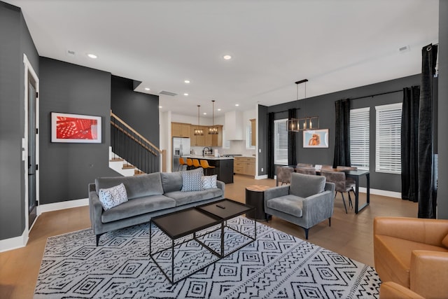 living room with sink, a chandelier, and light wood-type flooring