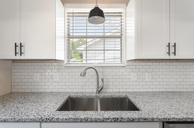 kitchen with sink, white cabinetry, light stone countertops, and decorative backsplash