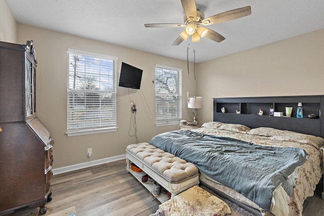 bedroom featuring ceiling fan, hardwood / wood-style floors, and multiple windows