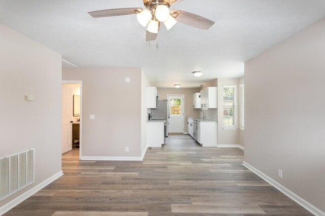 interior space featuring sink, white cabinets, light wood-type flooring, ceiling fan, and decorative backsplash