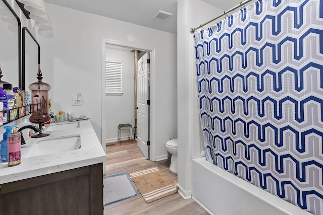 full bathroom with toilet, hardwood / wood-style floors, shower / bath combination with curtain, and vanity