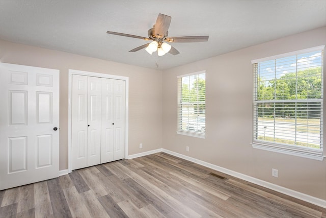 unfurnished bedroom featuring light wood-type flooring, ceiling fan, and a closet