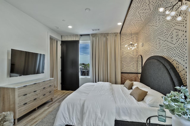 bedroom with light wood-type flooring and a chandelier