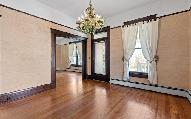 unfurnished room featuring a baseboard heating unit, a notable chandelier, and wood-type flooring