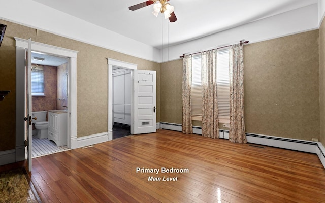 unfurnished bedroom with connected bathroom, a closet, ceiling fan, hardwood / wood-style flooring, and a walk in closet