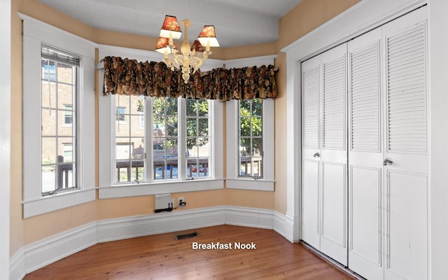 unfurnished dining area featuring wood-type flooring and a chandelier