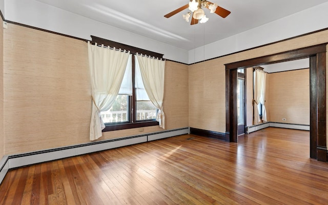 spare room with ceiling fan, baseboard heating, and hardwood / wood-style flooring