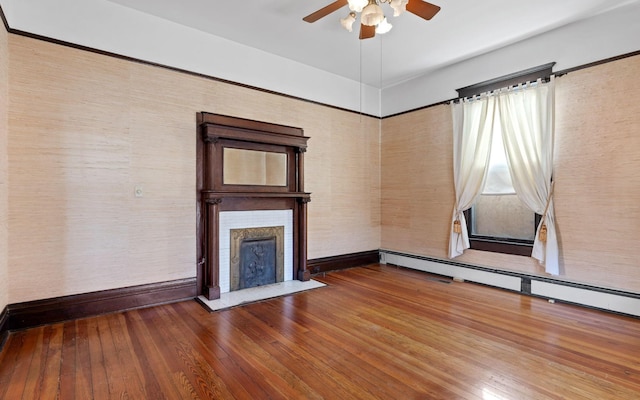 unfurnished living room with wood-type flooring, baseboard heating, and ceiling fan