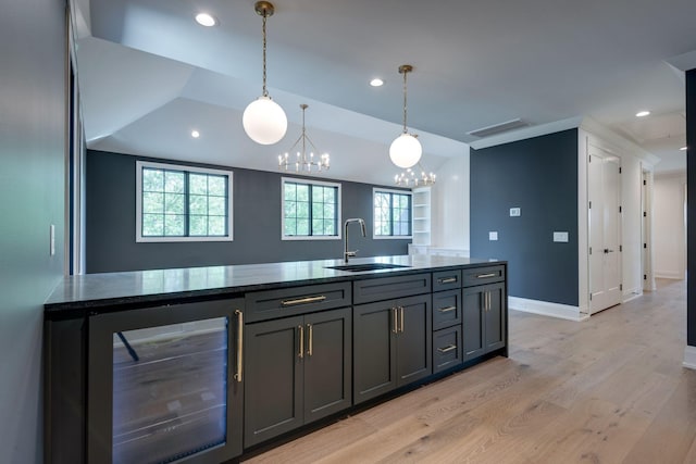 kitchen with a chandelier, pendant lighting, light hardwood / wood-style floors, beverage cooler, and sink