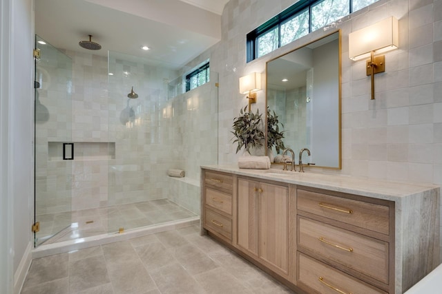 bathroom with vanity, tile walls, and a shower with shower door