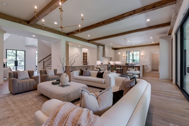 living room with light hardwood / wood-style flooring, an inviting chandelier, and beamed ceiling