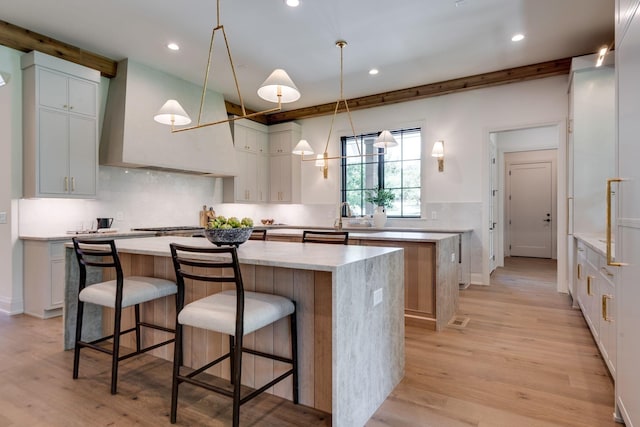 kitchen with white cabinets, premium range hood, a spacious island, and hanging light fixtures