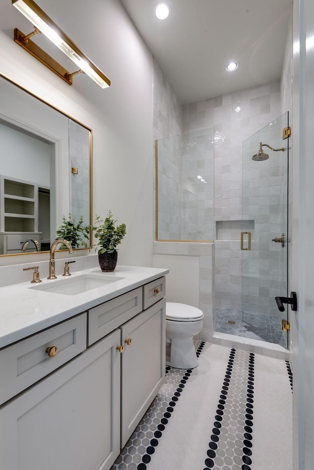 bathroom with toilet, vanity, tile patterned floors, and a shower with shower door