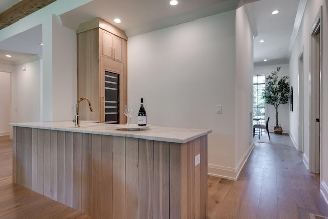 kitchen featuring sink, light brown cabinets, light hardwood / wood-style floors, and crown molding