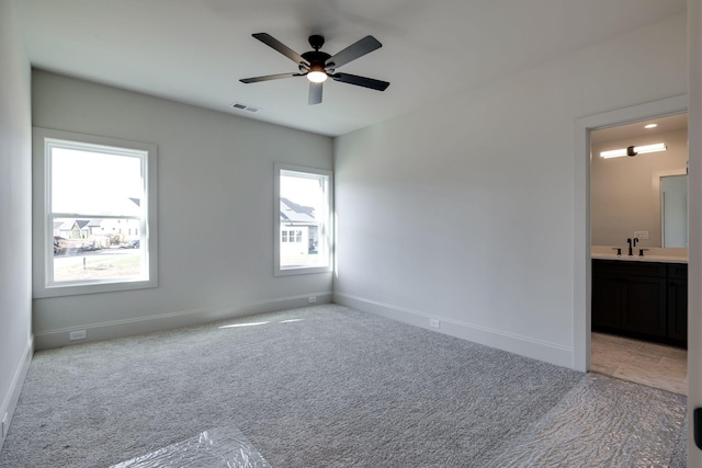 carpeted empty room featuring sink, ceiling fan, and plenty of natural light