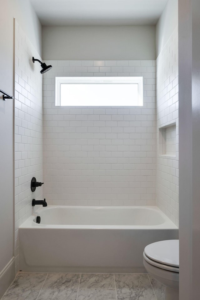 bathroom with tiled shower / bath combo, plenty of natural light, and toilet