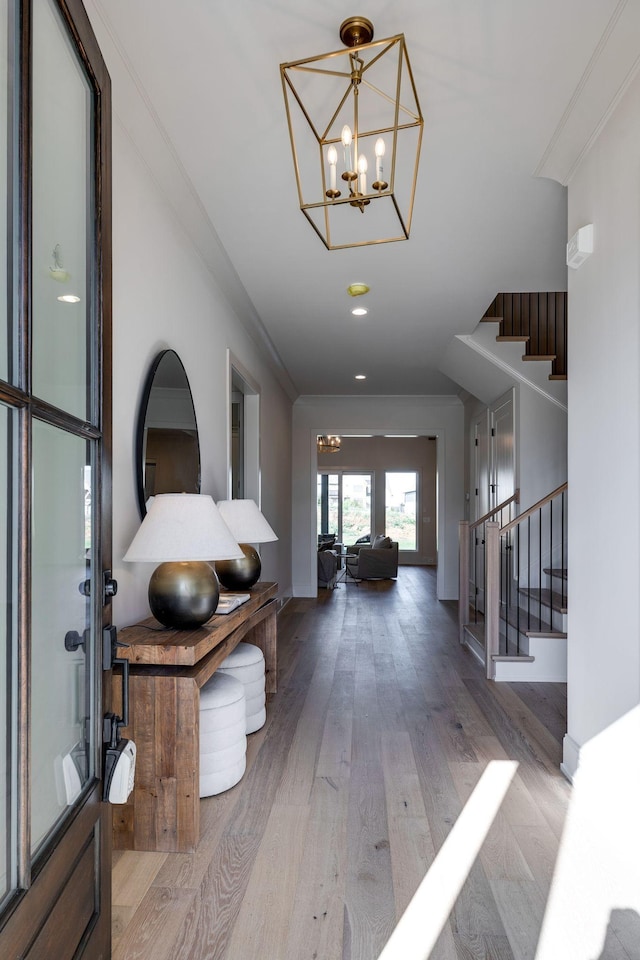 foyer featuring ornamental molding, light hardwood / wood-style floors, and a notable chandelier