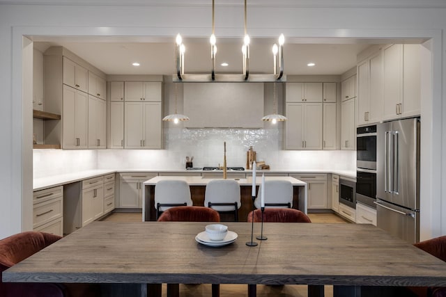 kitchen with pendant lighting, decorative backsplash, a center island with sink, a breakfast bar, and appliances with stainless steel finishes