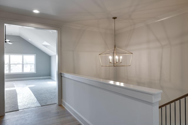 hall featuring lofted ceiling, an inviting chandelier, and hardwood / wood-style floors