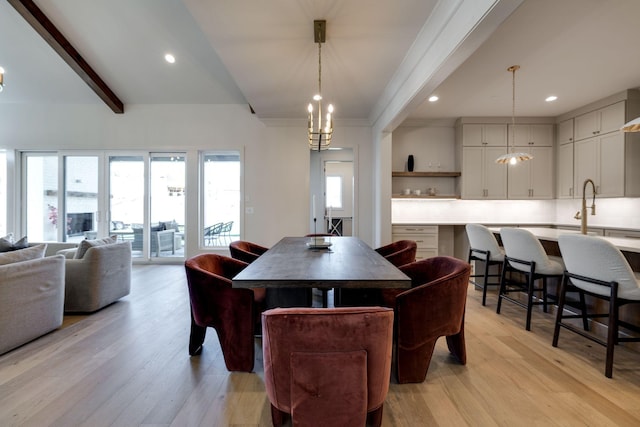 dining room with sink, light hardwood / wood-style floors, and beamed ceiling