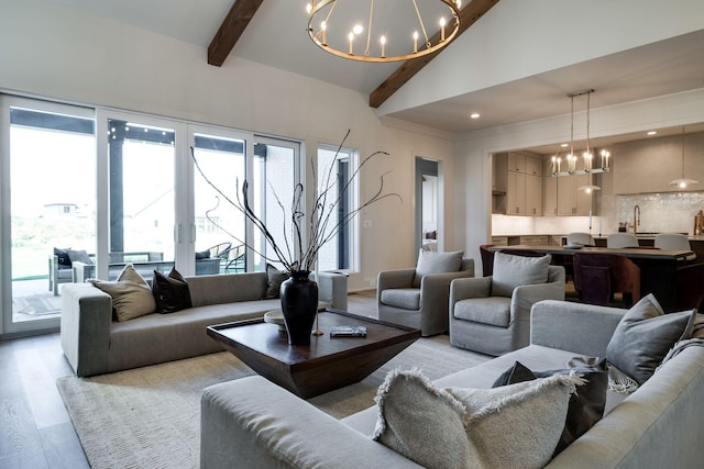 living room with sink, light hardwood / wood-style flooring, high vaulted ceiling, a notable chandelier, and beam ceiling