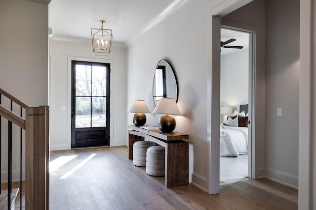 foyer with ceiling fan with notable chandelier, hardwood / wood-style floors, and crown molding