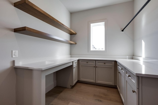 kitchen with dark wood-type flooring, kitchen peninsula, and gray cabinets