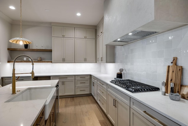 kitchen with tasteful backsplash, pendant lighting, stainless steel gas cooktop, and light stone countertops