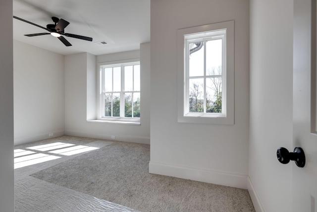 unfurnished room with ceiling fan, a wealth of natural light, and carpet