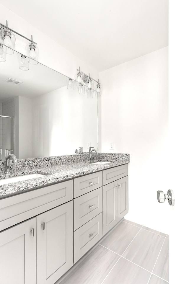 bathroom featuring tile patterned flooring, a shower with shower door, and vanity