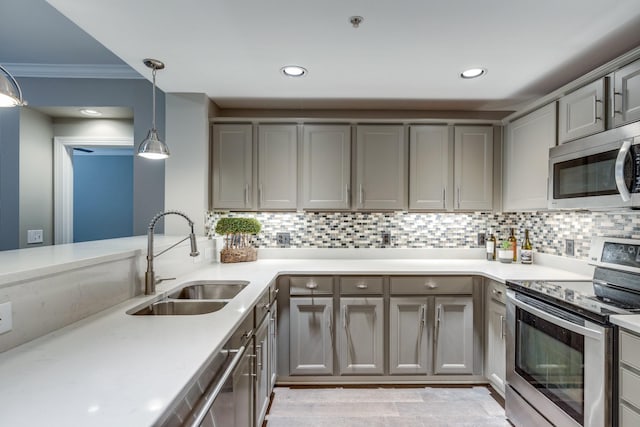 kitchen with appliances with stainless steel finishes, gray cabinetry, hanging light fixtures, sink, and backsplash