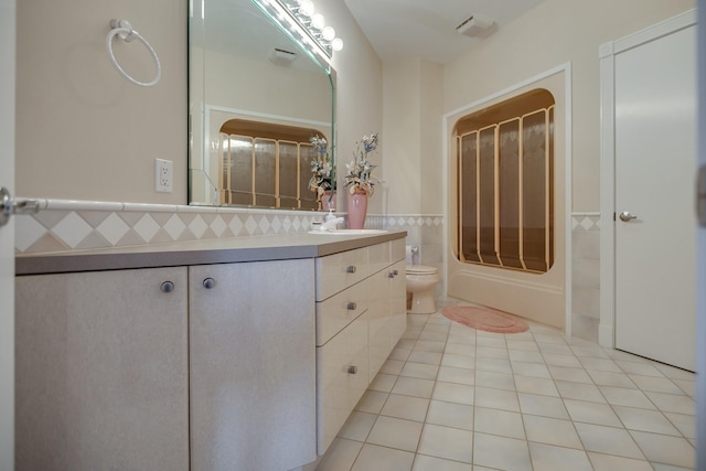 full bathroom featuring toilet, tile patterned flooring, tile walls, shower / bathtub combination, and vanity