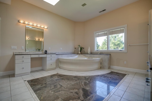 bathroom with a tub, a skylight, tile patterned floors, and vanity