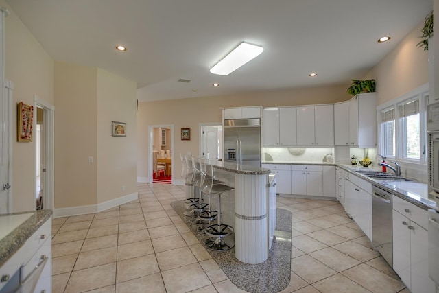 kitchen with a center island, stainless steel appliances, a breakfast bar area, white cabinets, and sink