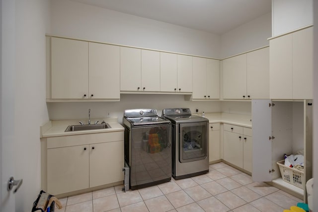 laundry area featuring sink, light tile patterned flooring, separate washer and dryer, and cabinets