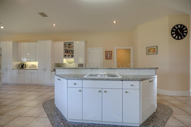 kitchen with white cabinetry, black electric cooktop, light stone counters, and an island with sink