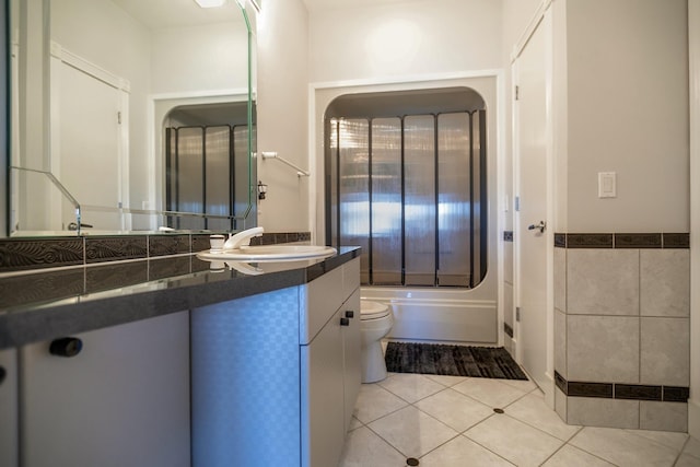 full bathroom featuring tile patterned flooring, washtub / shower combination, toilet, vanity, and tile walls