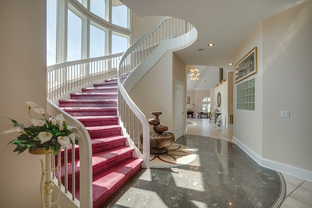 staircase with a high ceiling and a chandelier