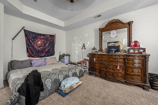 carpeted bedroom featuring ceiling fan, a textured ceiling, and a tray ceiling