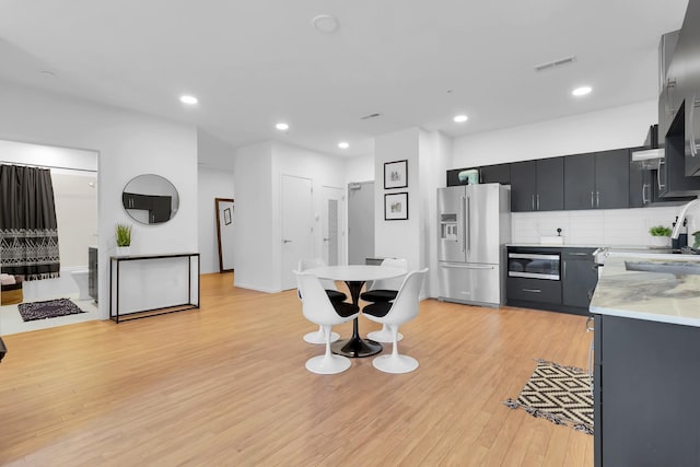 kitchen featuring sink, high quality fridge, tasteful backsplash, light hardwood / wood-style floors, and built in microwave