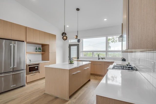 kitchen featuring vaulted ceiling, light brown cabinets, light hardwood / wood-style flooring, a kitchen island, and appliances with stainless steel finishes