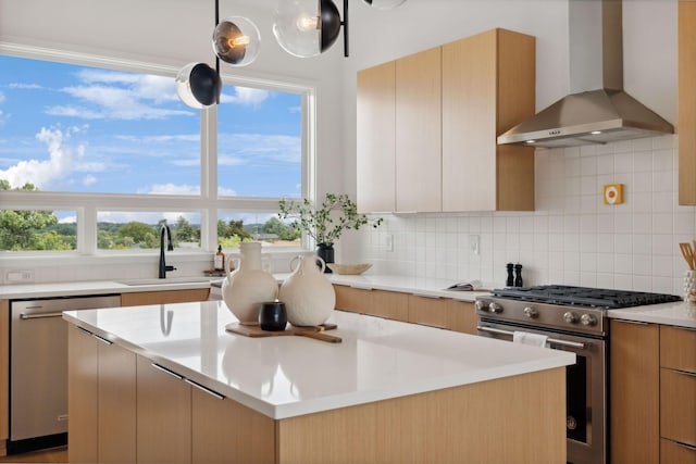 kitchen with sink, wall chimney exhaust hood, a kitchen island, and appliances with stainless steel finishes