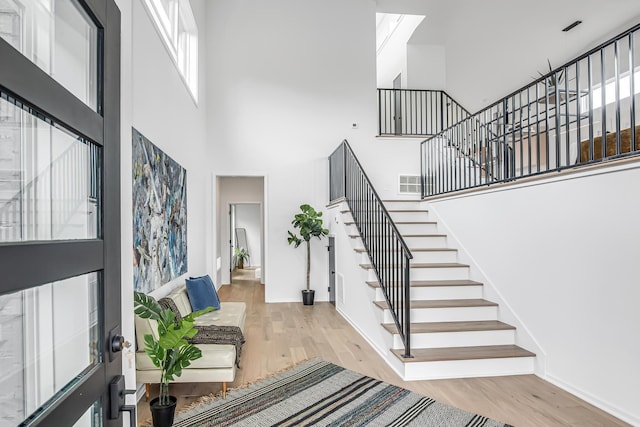 entrance foyer featuring a towering ceiling and light hardwood / wood-style floors