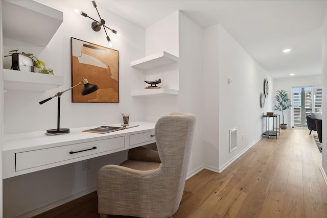 office with built in desk and light hardwood / wood-style floors