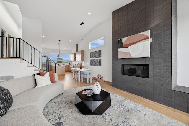 living room with vaulted ceiling, a fireplace, and light hardwood / wood-style floors