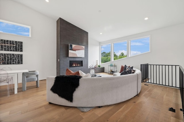 living room with light wood-type flooring, vaulted ceiling, and a large fireplace