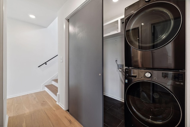 laundry room featuring hardwood / wood-style flooring and stacked washing maching and dryer