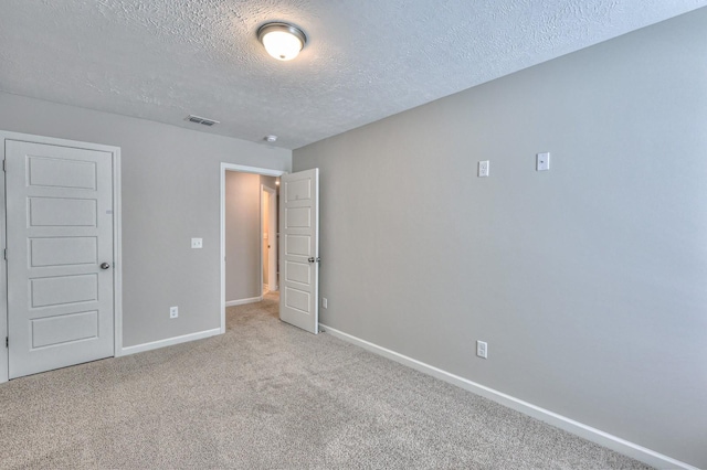 unfurnished bedroom featuring light colored carpet and a textured ceiling