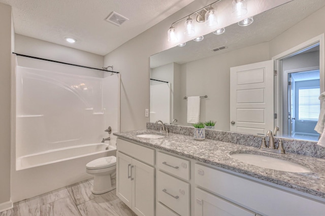 full bathroom featuring a textured ceiling, bathtub / shower combination, vanity, and toilet